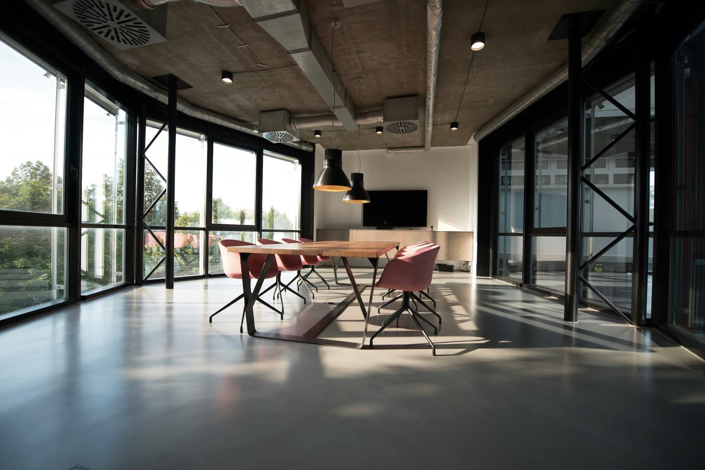 A modern glass-walled boardroom with a long table