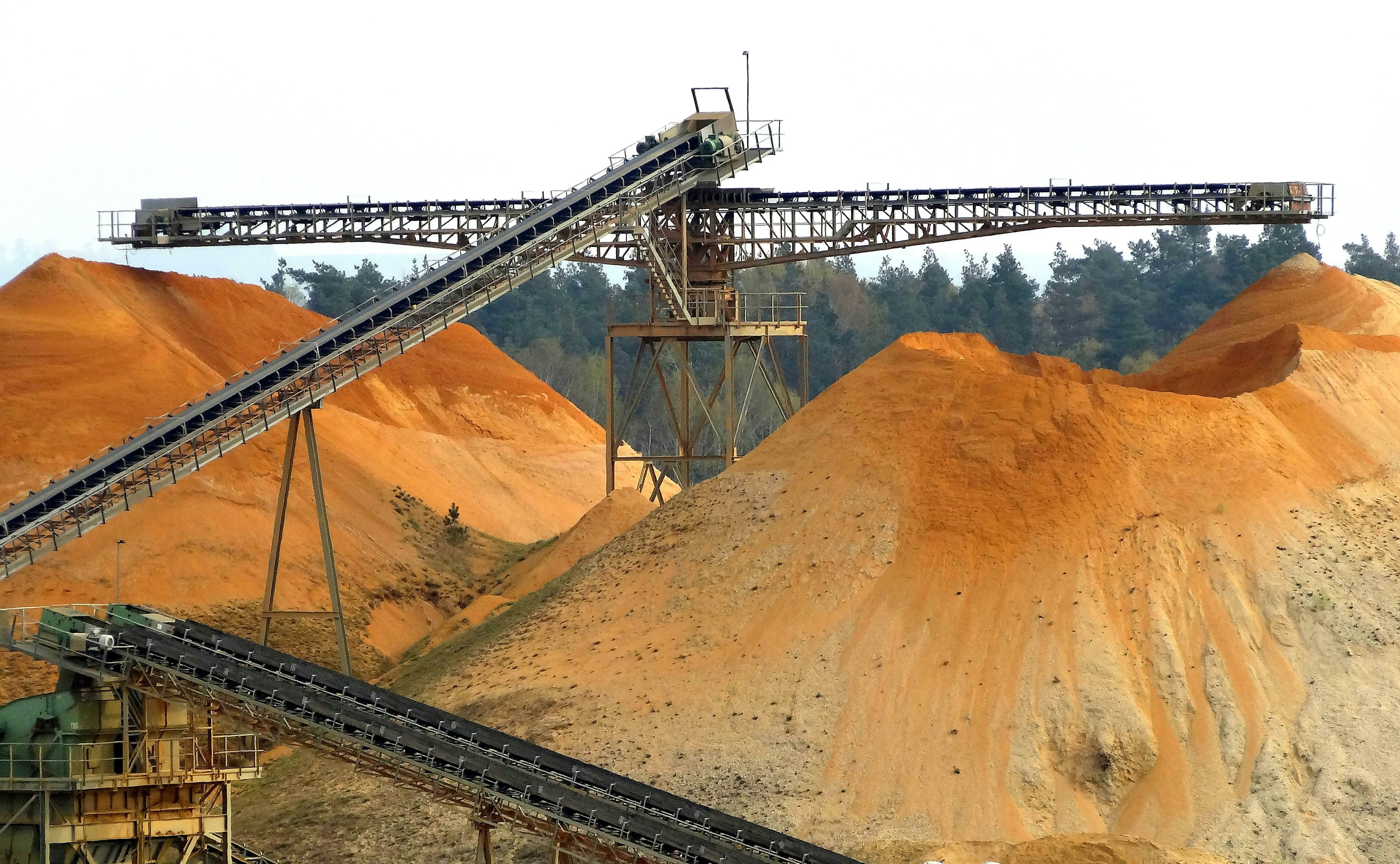 Conveyor belts over large piles of processed sand at a sand plant