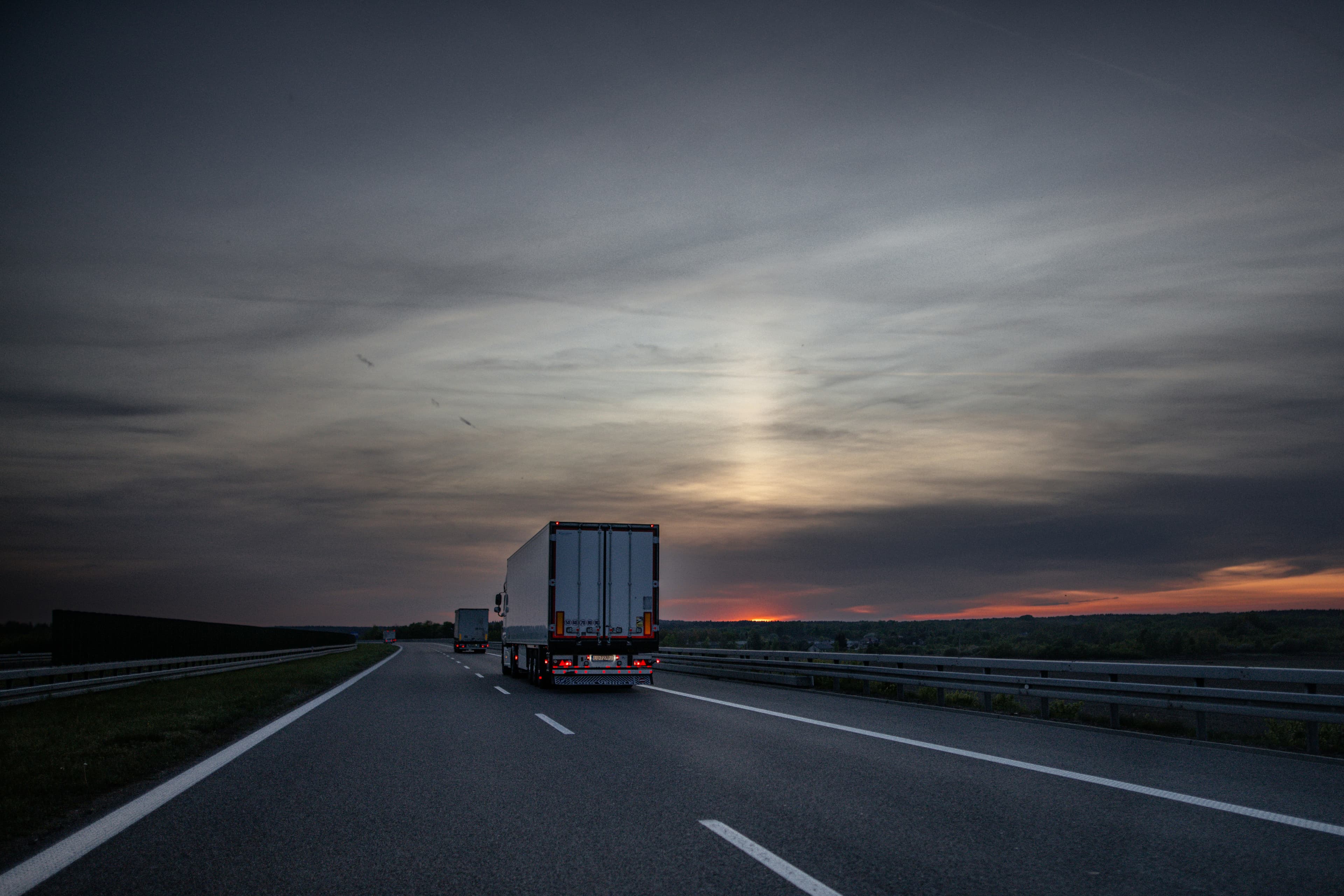 A lone truck on a wide highway at dusk