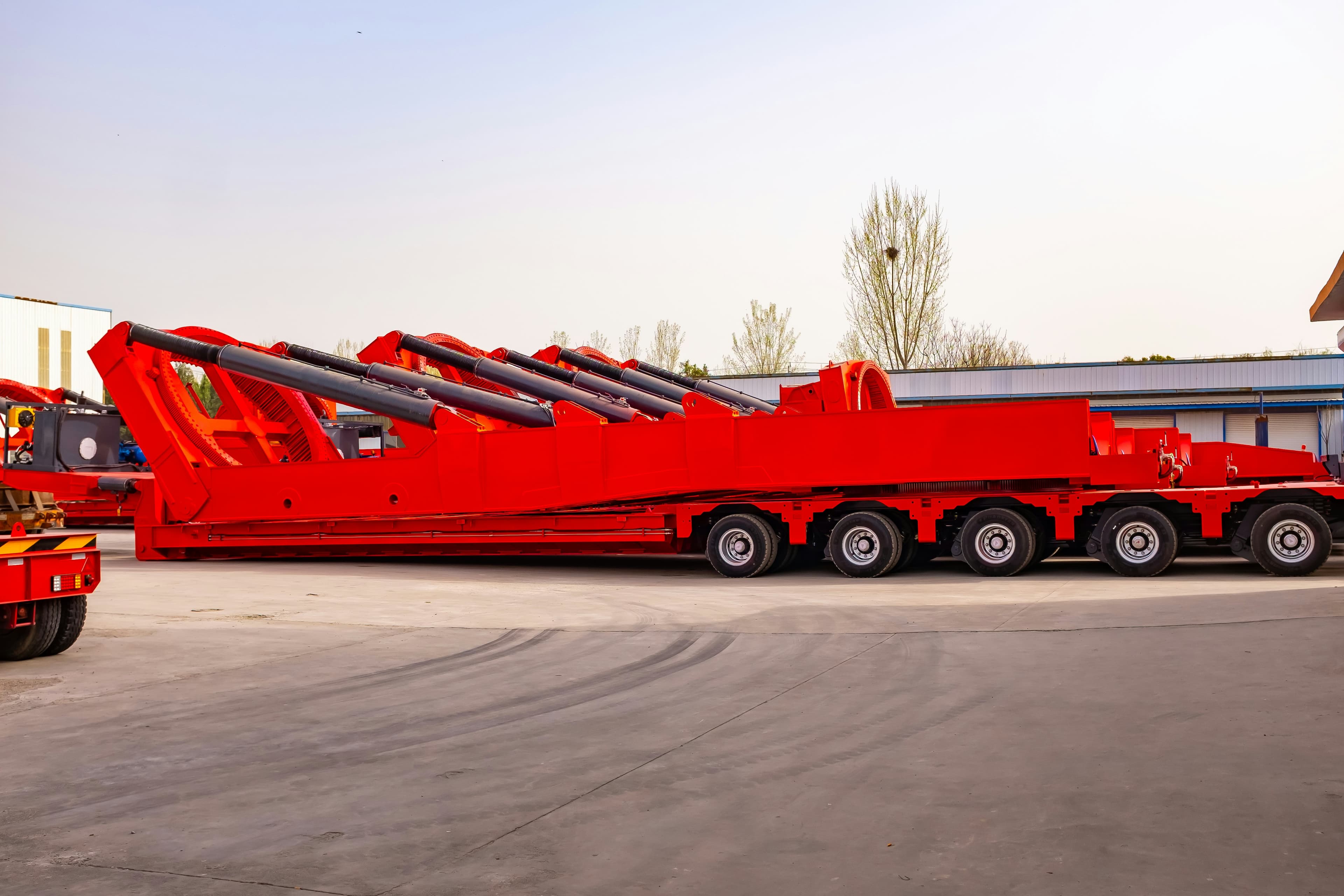 A row of red multi-axle heavy-haul trailers