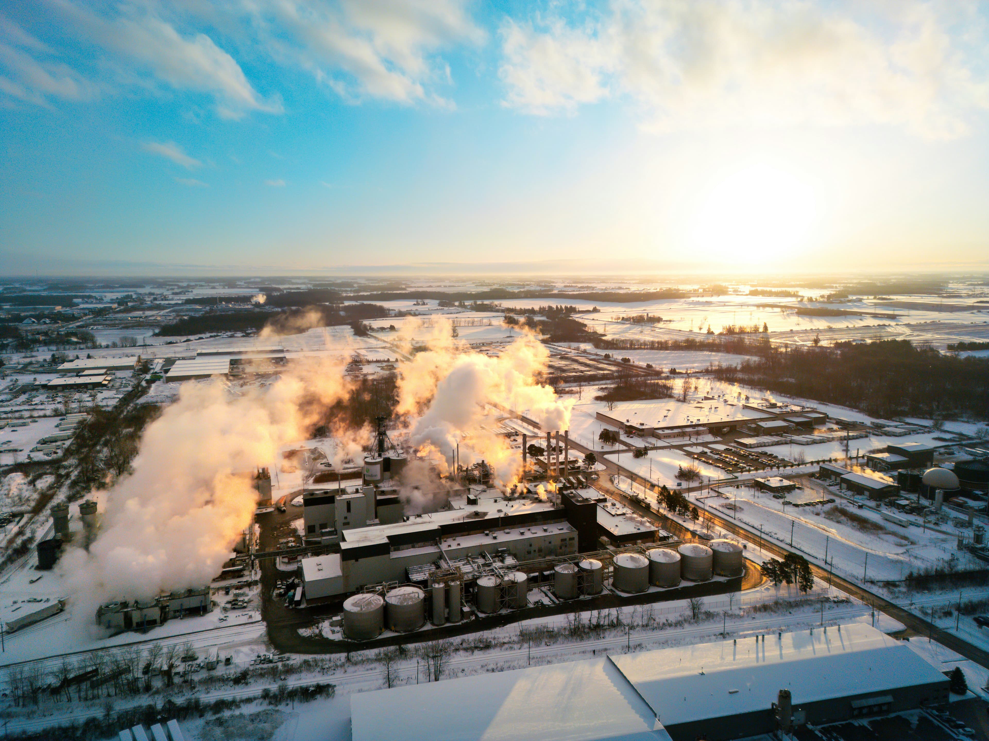 An industrial complex releasing steam into a bright winter sky