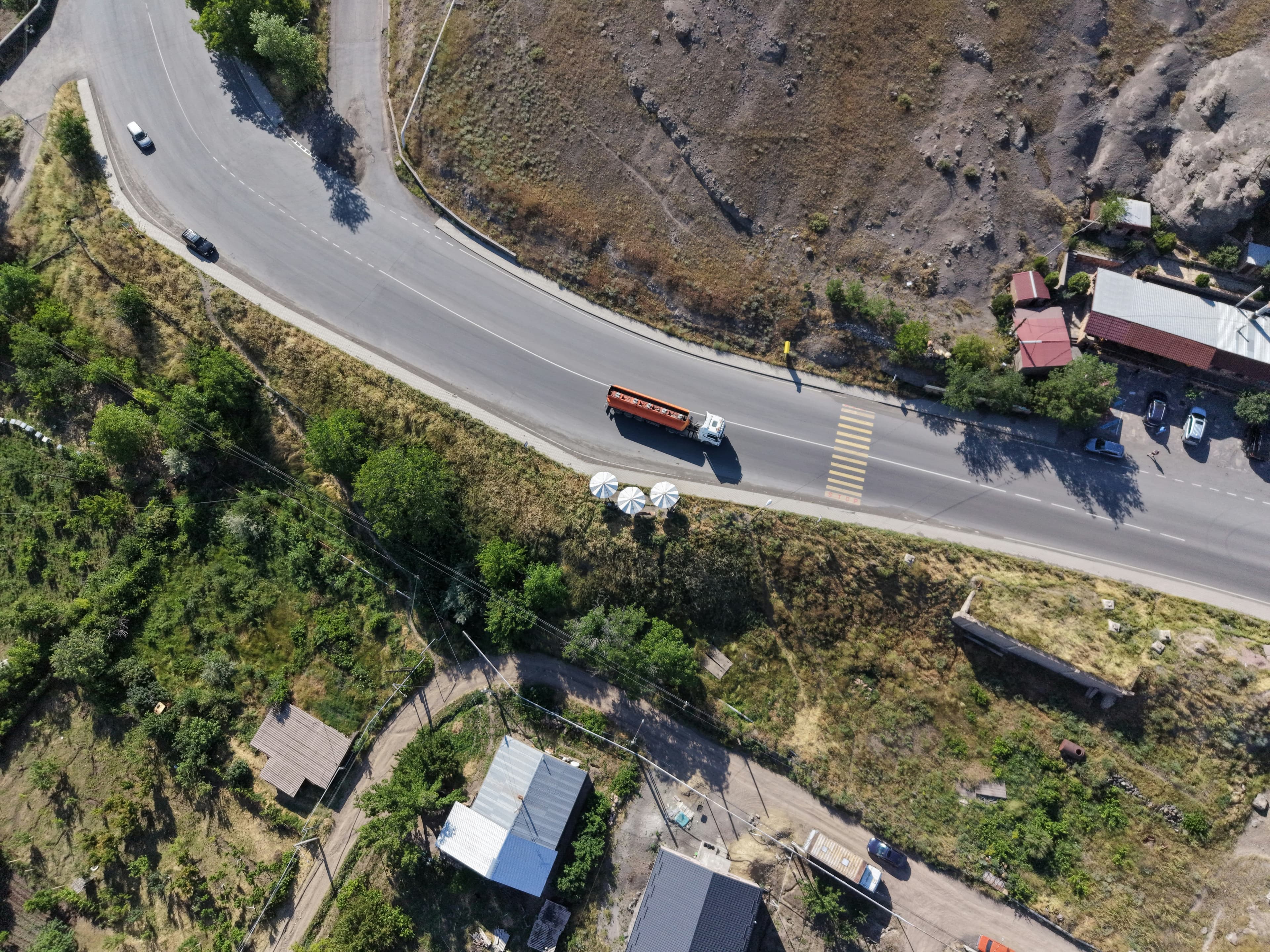 Aerial view of a highway curving through hills with trucks on it